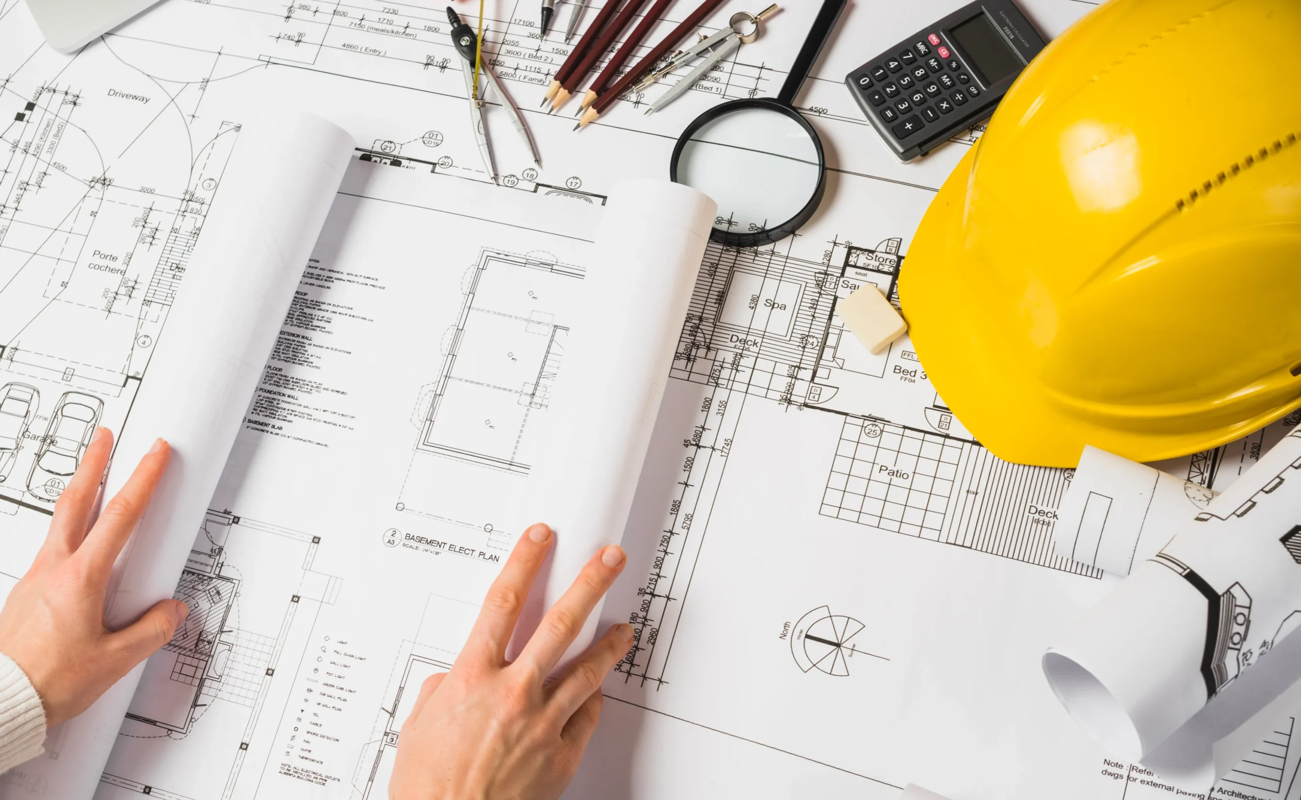 Engineer reviewing construction blueprints with drafting tools and safety helmet